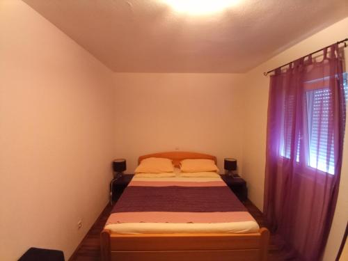 a small bedroom with a bed and a window at Apartmani Blažević in Zaglavice