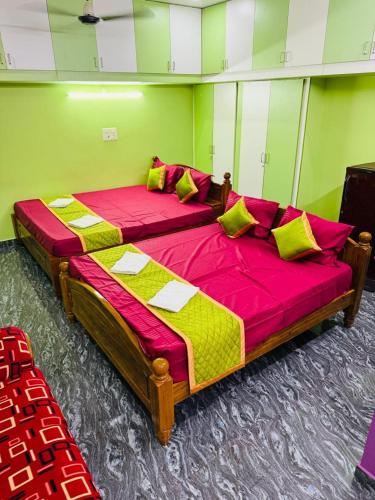 two beds in a room with red and yellow sheets at Eden Villa in Virāmpattinam