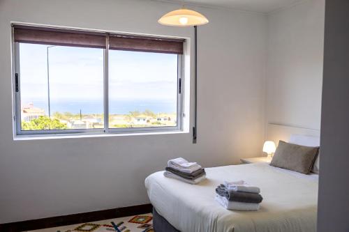 a bedroom with a window with a view of the ocean at Luz's Retreat Apartment in Ponta Delgada