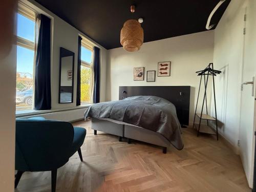 a bedroom with a bed and a chair and windows at Logement Langestreek in Lemmer