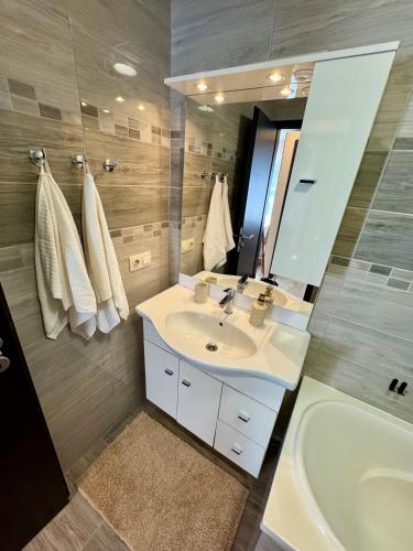 a bathroom with a sink and a tub and a mirror at Ditta Home in Nyíregyháza