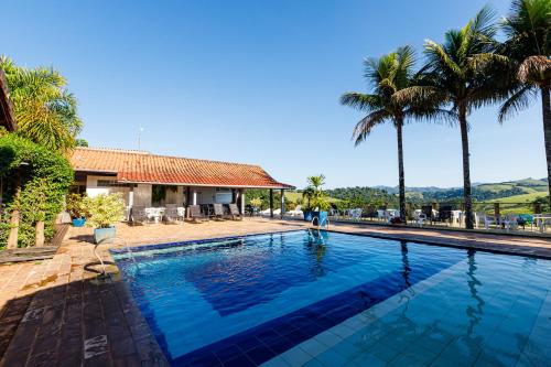 a swimming pool with palm trees and a house at Cabanas do Morro in Serra Negra
