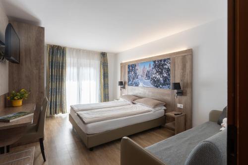 a hotel room with two beds and a desk at Hotel Alpen in Andalo