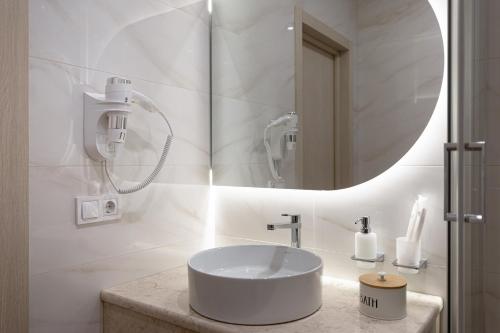 a white bathroom with a sink and a mirror at Leomare in Odesa