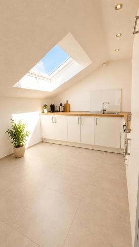 an attic kitchen with white cabinets and a skylight at Allgäu Ferienhaus 5 Apartments mit Sauna,Balkon, Garten und Privatparkplatz in Blaichach