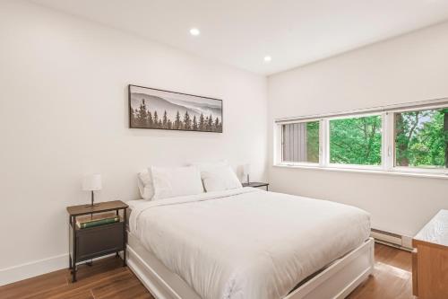 a white bedroom with a bed and two windows at 206 Val-des-Neiges - MSA LUX in Beaupré