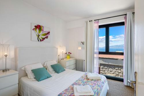 a white bedroom with a bed and a large window at Villa Aster in Coti-Chiavari