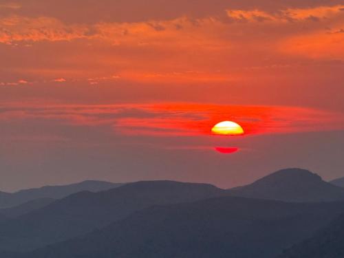 a sunset over mountains with the sun in the sky at HT Innhabit rooftop view suite in Medicine Park