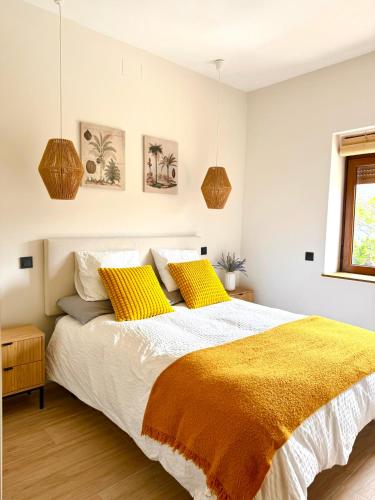 a bedroom with a large bed with yellow pillows at Casa BuganVilla de Gredos in Mombeltrán