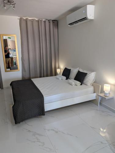 a white bedroom with a white bed and a window at Shamrock Flats in Mellieħa