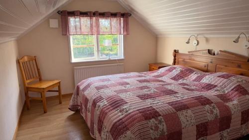 a bedroom with a bed and a chair and a window at Mysigt torp på bondgård in Lämmedal