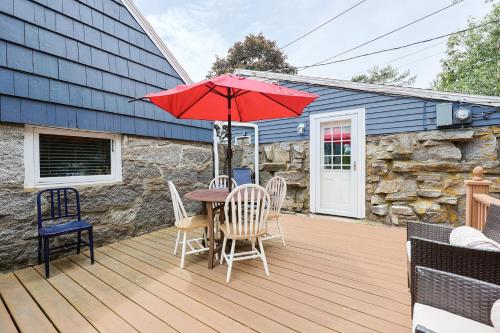 a wooden deck with a table with a red umbrella at Granite Cottage in Rockport