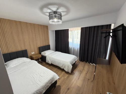 a hotel room with two beds and a chandelier at New Venus in Curtea de Argeş