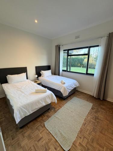two beds in a room with a large window at Stirling House in Mooiriver