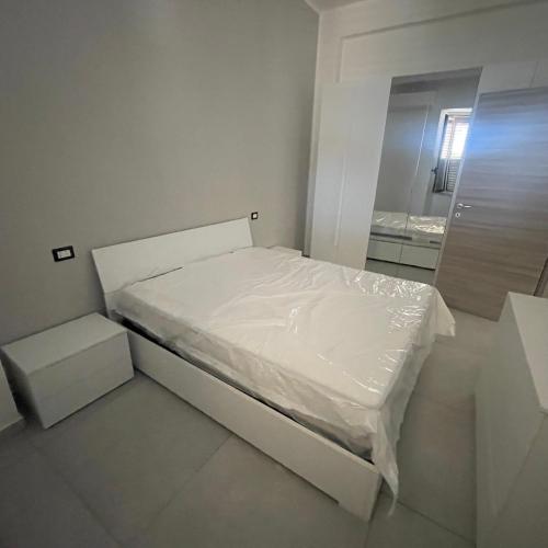 a small white bed in a room with a mirror at Casa vacanze joppolo in Ioppolo