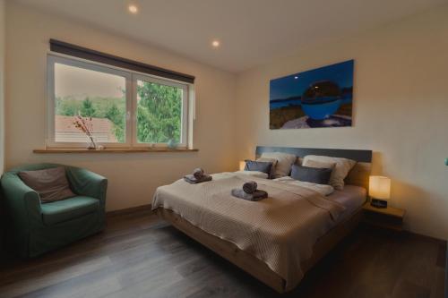 a bedroom with a bed and a chair and a window at Ferienwohnung Auszeit Osterode in Osterode