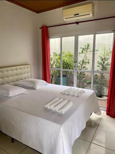 a bedroom with a bed with white sheets and a window at Hotel Vitoria in Matupá