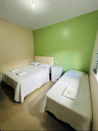 two beds in a room with green walls at Hotel Vitoria in Matupá