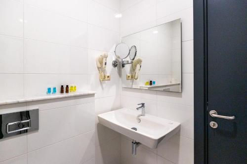 a white bathroom with a sink and a mirror at Riverside Hotel & Restaurant in Acharistsqali