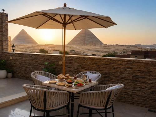 a table with food and an umbrella with pyramids in the background at Oyal Scarab Pyramids View in Cairo