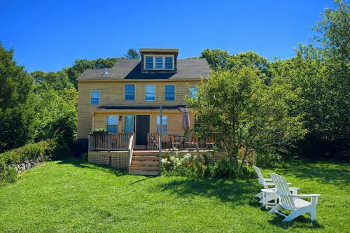a house with two white chairs in the yard at River Watch in Gloucester