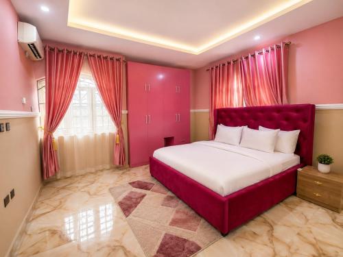 a bedroom with a red bed in a pink room at IMSMART Luxury Apartment in Uyo
