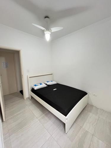 a white room with a bed with a ceiling fan at Casa Ferry Piscina Privativa e Hidro 300m da Praia in Praia Grande