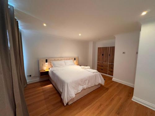 a bedroom with a large white bed and wooden floors at Cosy 2 Story Home Leicester City Centre in Leicester