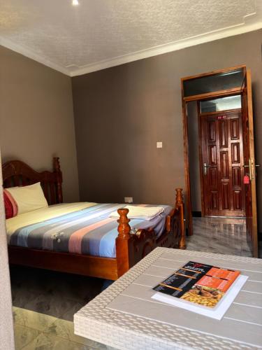 a bedroom with a bed and a table and a door at Skylab Accomodationz in Kasangati