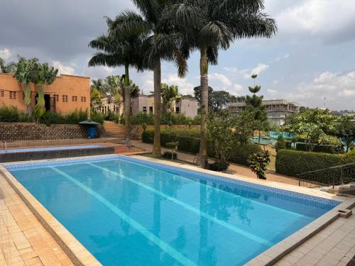 a large swimming pool with palm trees and buildings at Skylab Accomodationz in Kasangati