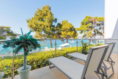a balcony with a table and chairs and a palm tree at Lumbarda Resort Apartments in Lumbarda