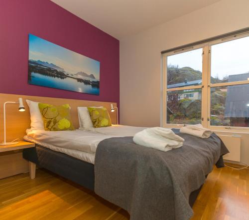 Fast Hotel Lofoten في سفولفير: غرفة نوم بسرير وجدار ارجواني