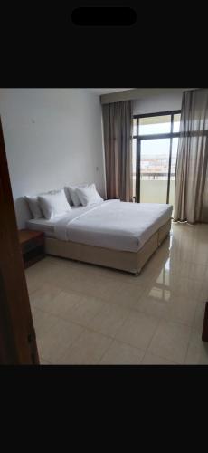 ein großes Bett in einem Zimmer mit einem großen Fenster in der Unterkunft Private flats in Salalah