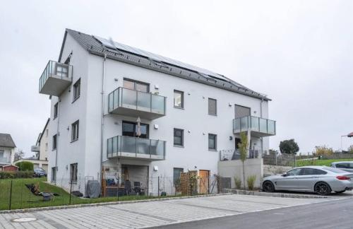 a white building with a car parked in front of it at Design-Apartment in Langenbach bei München, nahe Flughafen München in Langenbach