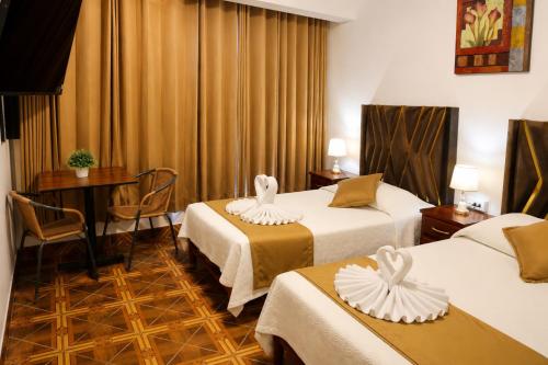 a hotel room with two beds and a table at Villa Fernanda Hotel in Tacna