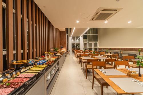 a restaurant with tables and chairs and a buffet at Hotel Laghetto Moinhos in Porto Alegre