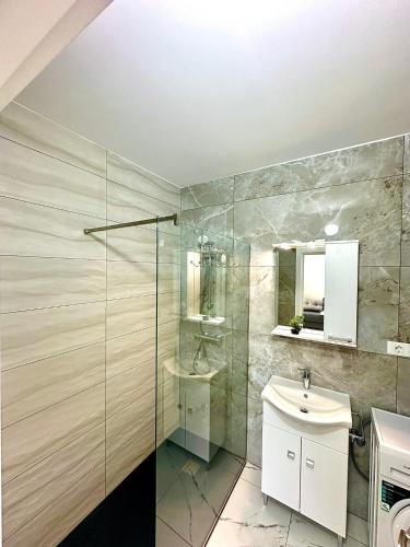a bathroom with a sink and a glass shower at North Boutique Apartments in Mamaia Sat/Năvodari