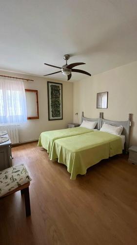 a bedroom with a green bed and a ceiling fan at Casa la Paloma in Es Caló