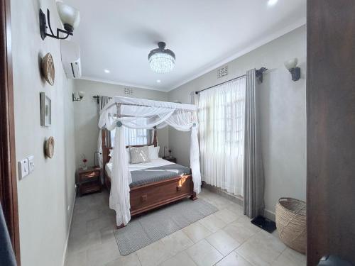 a bedroom with a canopy bed and a window at The Angelique Oasis in Arusha