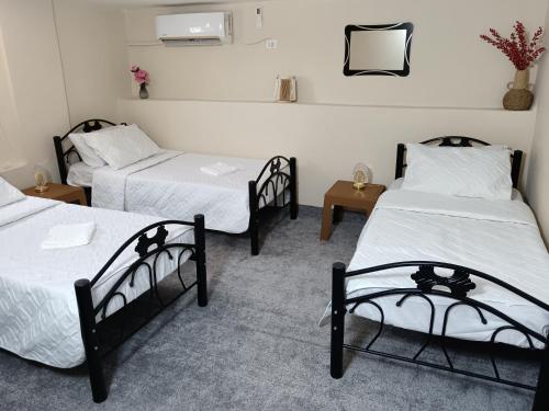 a room with three beds and two tables at Rousan House in Um Qeis