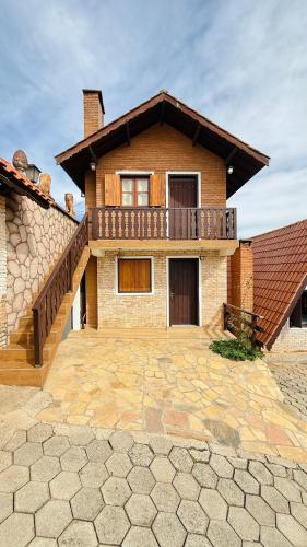 a brick house with a balcony on top of it at Pousada Florada do Amanhã in Monte Verde