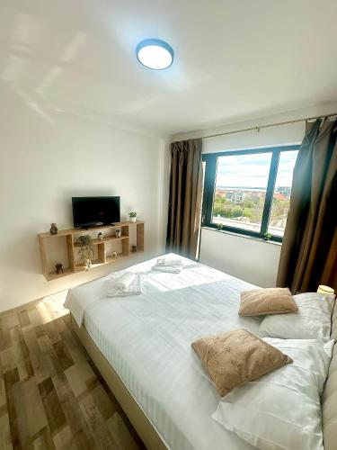 a bedroom with a large white bed with a window at North Boutique Apartments in Mamaia Sat/Năvodari