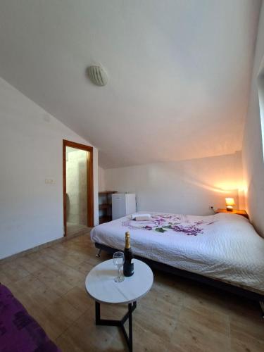 a bedroom with a bed and a table with a bottle of wine at Mia in Glavatske Kućice