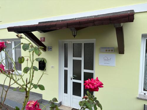 awning over the door of a house with pink flowers at Apartma Suzy in Bovec