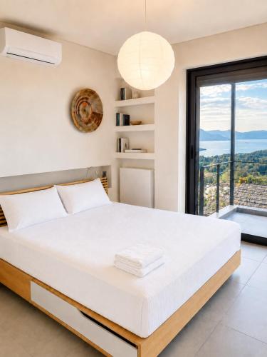 a bedroom with a large white bed and a large window at Óros Residence - Pool & Panoramic Views in Tzíkidhes