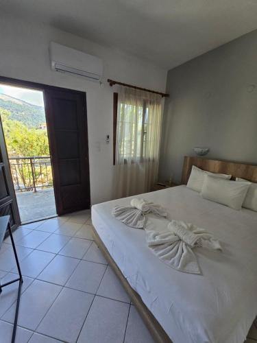a bedroom with a bed with white sheets and a window at Pension Assos in Koinyra