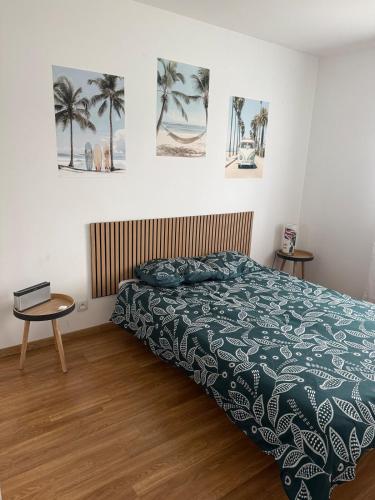 a bedroom with a bed and a table and pictures on the wall at Maison au calme in La Roche-sur-Yon
