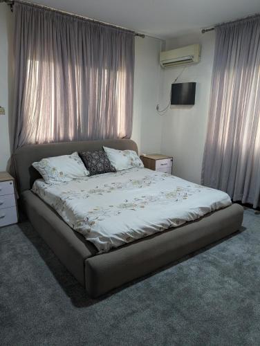 a bed in a bedroom with curtains and a television at Ivaeli Apartment in Lagos