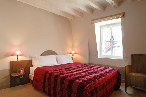 a bedroom with a bed with a red blanket and a window at Hôtel L'Adresse in Tours