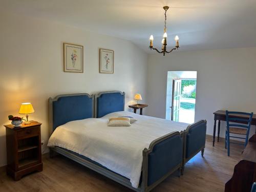a bedroom with a bed with a blue headboard and a table at Maison Mélusine in Londigny